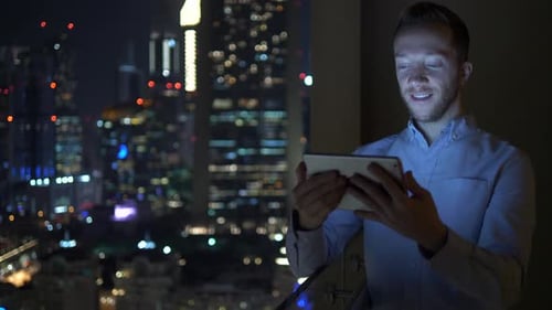 Young Man Using Tablet at Night City View