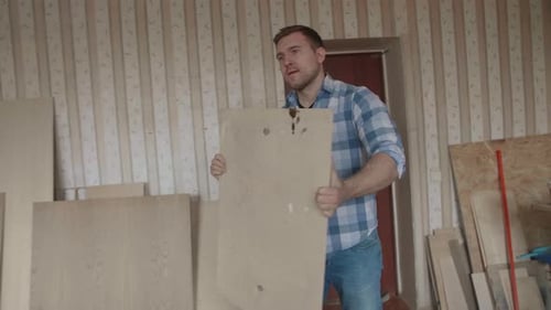 Man Carries Plywood in Workshop