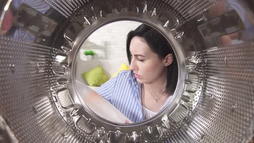 Woman Inspects Stained Laundry in Washing Machine Drum