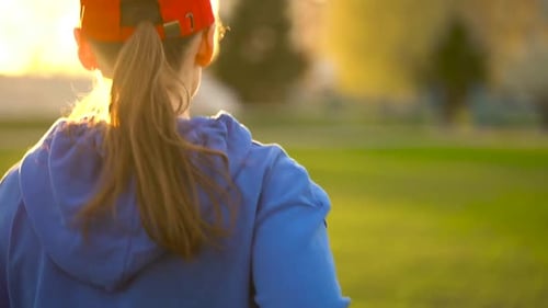 Woman Runs Through the Stadium at Sunset Back View