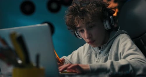 Boy Doing Homework with Laptop and Headphones