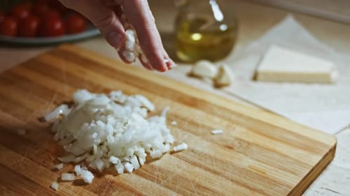 Hand Sprinkling Diced Onion on Wooden Board