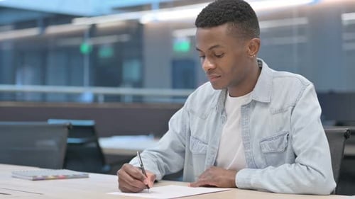 Young Adult Writing on Paper at Desk
