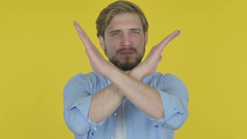 Young Adult Man Gesturing No Against Yellow Background