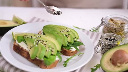 Sprinkling Sesame Seeds onto Gourmet Avocado Toast