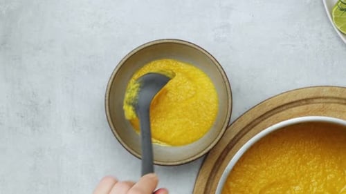 Scooping Yellow Soup into Bowl Overhead Shot