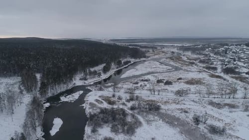 Vue aérienne de la rivière d'hiver près de la forêt. Dans le village lointain. Plutôt nuageux 02