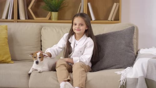 Young Girl Loving Pet Dog on Couch