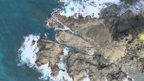 Aerial View of Waves Crashing on Rocky Coastline