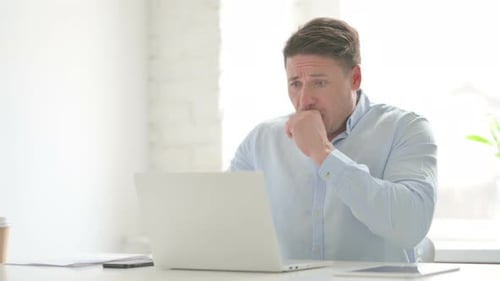Man Coughing while using Laptop in Office