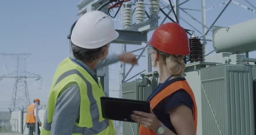 Mature Engineers Examining Data and Power Station Equipment