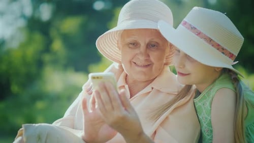 Grandmother and Grandchild Looking at Phone Together Outdoors