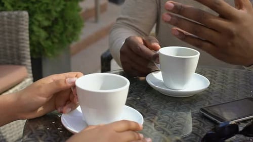 Schwarzer Mann spricht mit Frau, die im Café sitzt, Kollegen trinken zusammen Kaffee