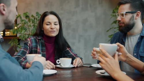 Men and Women Clinking Cups and Enjoying Drinks Sitting in Cafe Together Talking Laughing