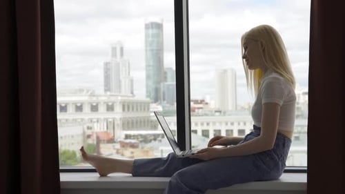 Woman Video Conferencing on Laptop by City View Window