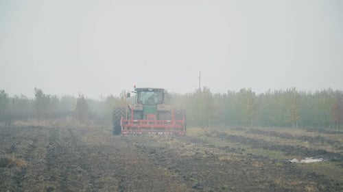 Tractor Tilling Field on Overcast Day
