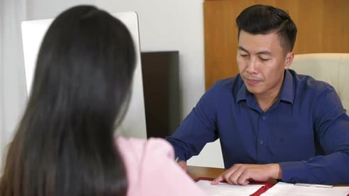 Man Discusses Paperwork with Woman in Office
