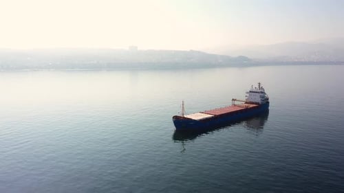 Leeres Frachtschiff mit morgendlichem Blick auf die Stadt im Hintergrund