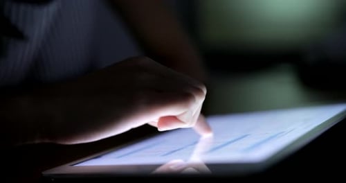 Hand Interacting With Data on Tablet at Night