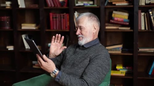 Side View of Cheerful Mature Adult Male Having Online Video Chat By Digital Tablet