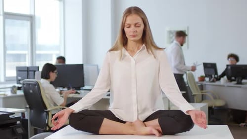 Businesswoman Meditating on Desk in Office
