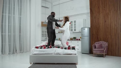 Happy Couple Jumping on Bed in Pajamas