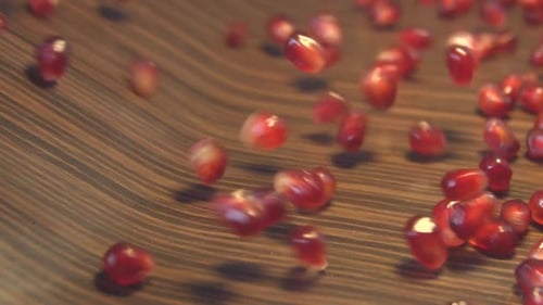 Fresh Pomegranate Seeds Pouring onto Brown Surface
