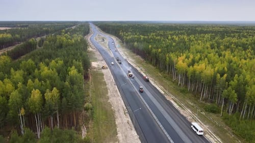 Highway upgrade. Laying new asphalt on a forested section of an intercity road