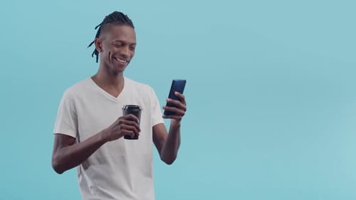 Young Adult Uses Phone, Drinks Coffee in Studio