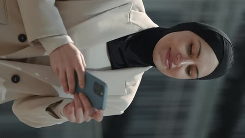 Muslim Woman Typing Messages on Cell Phone Outdoors