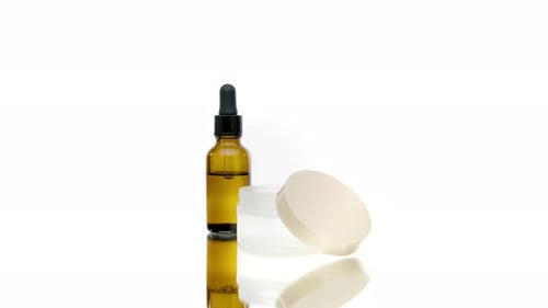 Frasco de líquido para botellas cosméticas que gira sobre fondo blanco, aceite corporal, crema natural