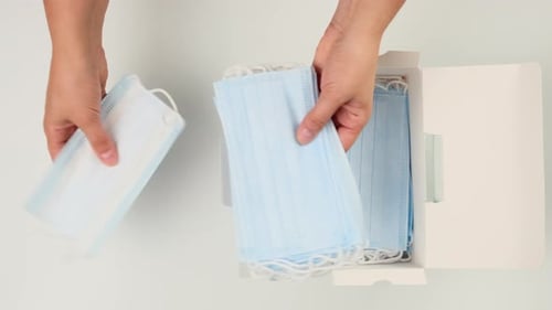 Hands Remove Surgical Masks from Box Overhead