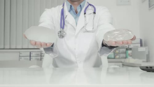Doctor Holding Silicone Breast Implants in Office