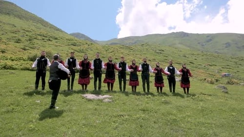 Adults Dance in Traditional Clothing on Mountain Field