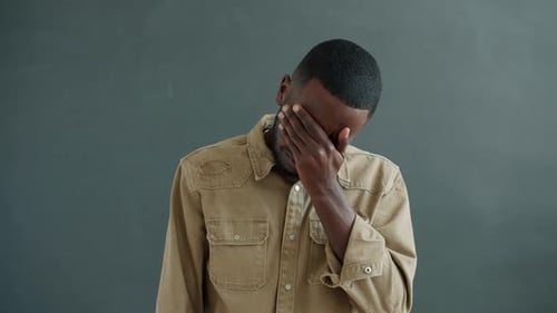 Zeitlupe eines unglücklichen afroamerikanischen Mannes, der mit traurigem Gesicht in die Kamera blickt