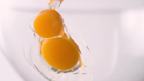 Egg Yolks Falling into Glass Bowl with Water