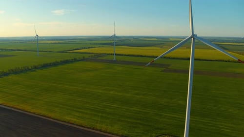 Wind Generators Among Green Fields Producing Eco Renewable Electricity