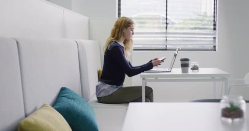 Woman Working on Laptop and Talking on Phone
