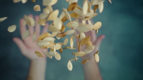 Hands Toss Pumpkin Seeds into the Air