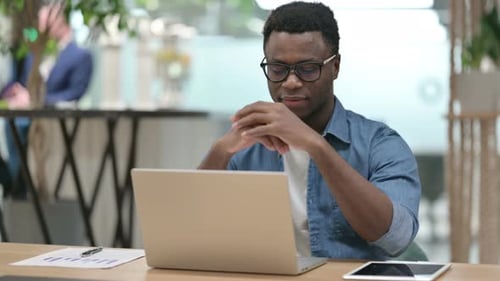 Smiling Man Working on Laptop in Modern Office