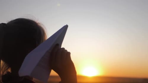 Happy Little Girl Playing with a Paper Airplane Outdoors During Sunset. Concept Big Child Dream
