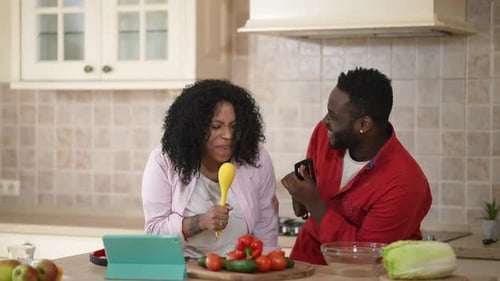 Energetic Couple Singing with Kitchen Utensils
