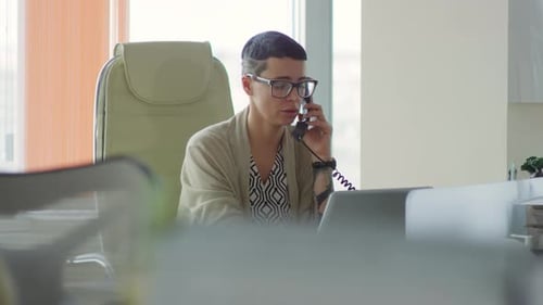 Woman Talking on Phone While Using Laptop