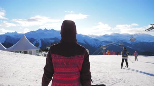 Eine junge Frau auf einem Snowboard auf dem Gipfel eines Berges auf einer Skipiste