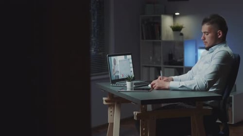 Profile View of Concentrated Man Listening to His Boss on Video Call on Computer
