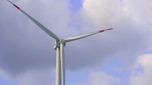Wind Turbine Spinning Against Blue Cloudy Sky