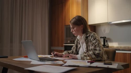 Zoom Camera A Woman with Glasses Works Remotely From Home Sitting at a Table with a Laptop and a