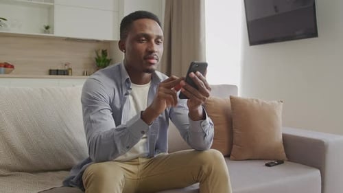 Man Using Smartphone on Couch at Home