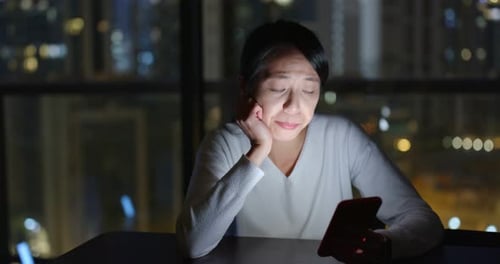 Woman Using Smartphone While Yawning at Night