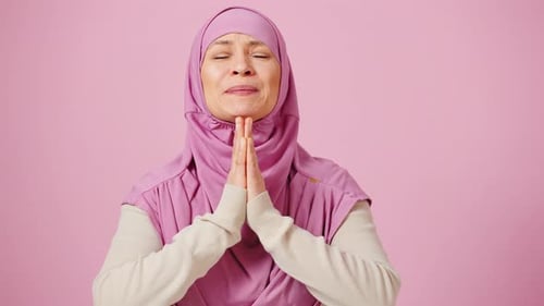 Emotionale muslimische Frau mittleren Alters im traditionellen Kopftuch, die zu Gott betet und sagt, bitte machen